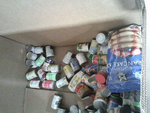 Cans and big bag of pancake mix on the bottom of a cardboard container.